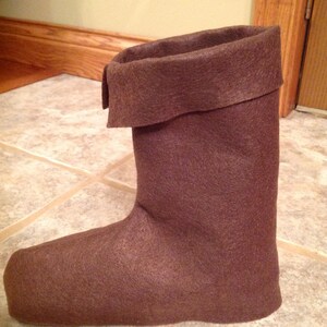 May include: A brown felt boot with a folded-over top. The boot is made of a soft, fuzzy material.