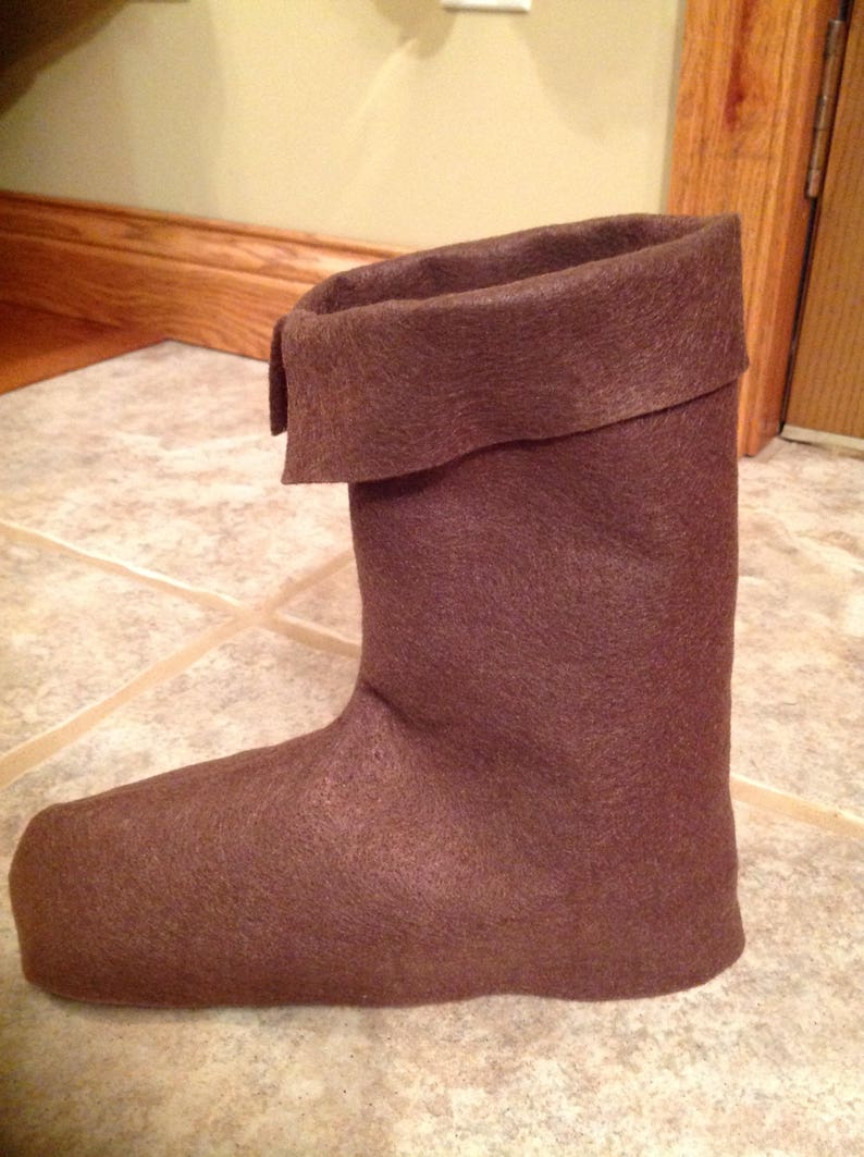 May include: A brown felt boot with a folded-over top. The boot is made of a soft, fuzzy material.