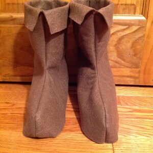 May include: A pair of brown felt boots with a folded-over top.