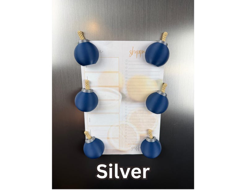 May include: Six dark blue spherical magnets with silver-coloured tops and tan rope-like fuses, arranged in pairs on a white shopping list notepad with orange text and citrus graphics. The word Silver is printed in white at the bottom of the image.