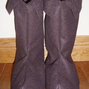 May include: A pair of brown fleece boot cuffs. The cuffs are folded over at the top and have a seam down the back.