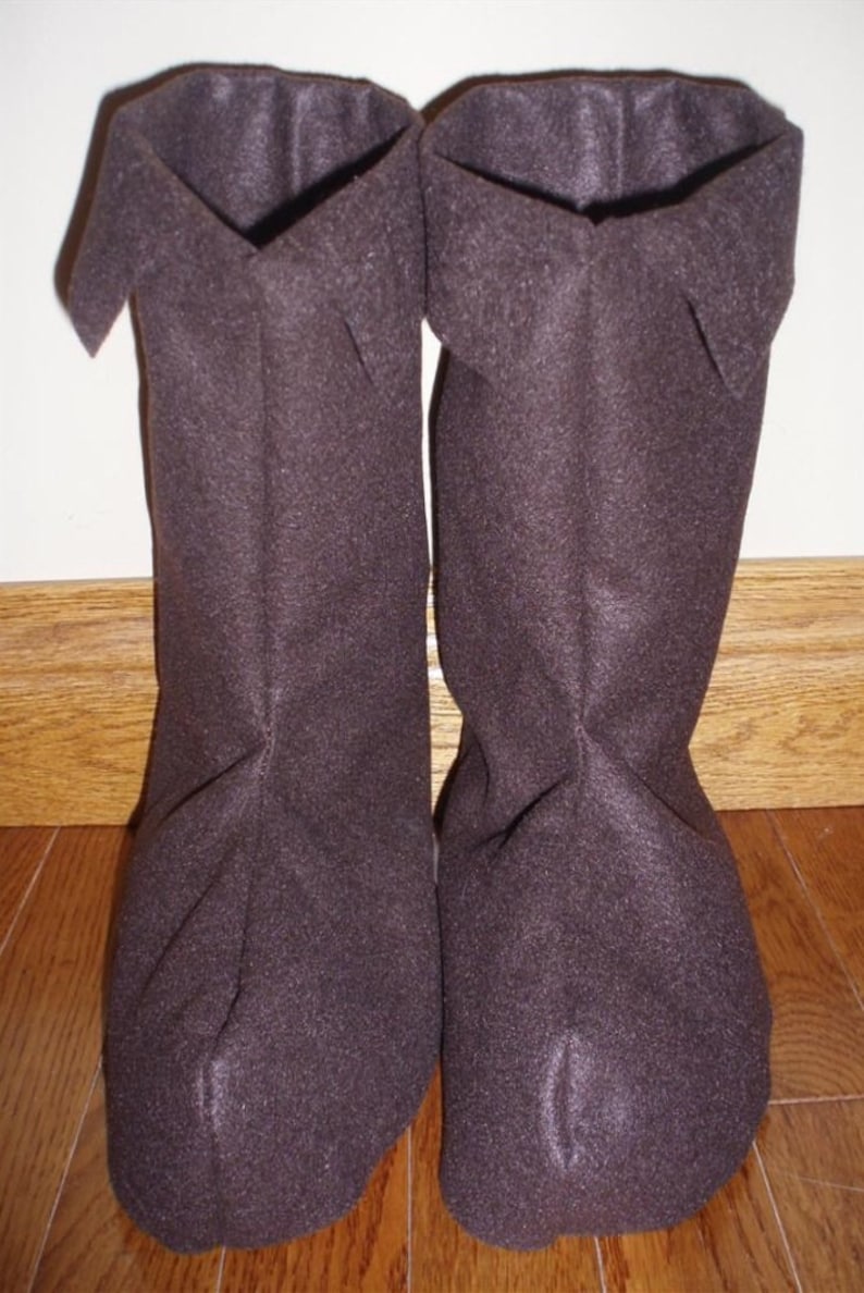 May include: A pair of brown fleece boot cuffs. The cuffs are folded over at the top and have a seam down the back.