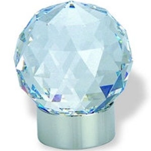 Peut inclure: Un bouchon de bouteille en cristal bleu clair avec un design facetté et une base argentée.