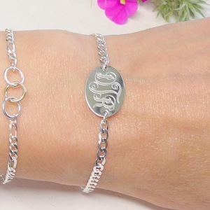 May include: Two silver-toned chain bracelets. One bracelet features three interlocking circular links, including one gold-toned ring. The second bracelet features a central oval-shaped metal plate engraved with the stylized script letters DJR.