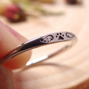 May include: Silver ring with a paw print and two angel wings engraved on the band.