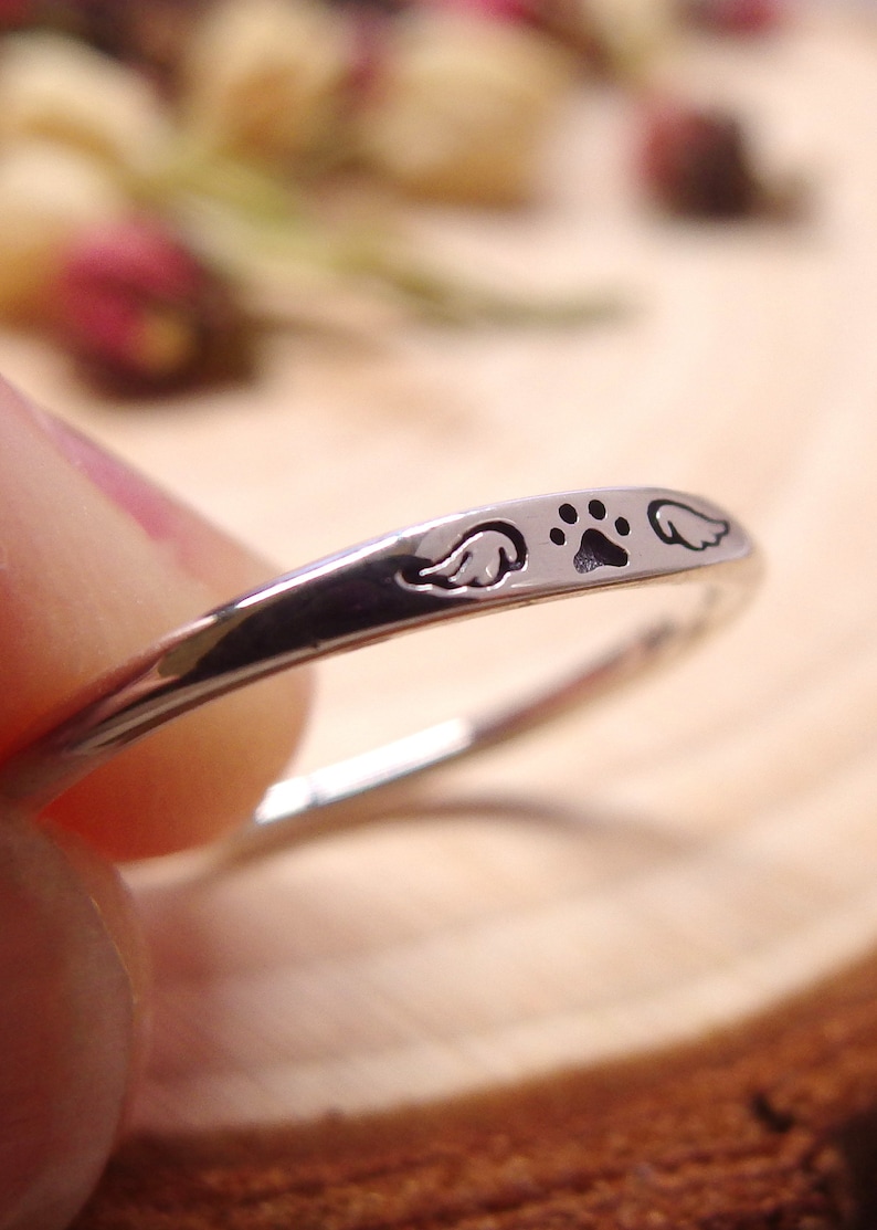 May include: Silver ring with a paw print and two angel wings engraved on the band.