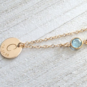 May include: Gold necklace with a round pendant engraved with the letter "C" and the date "09.21.78". A small light blue gemstone is attached to the chain.