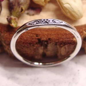 May include: A silver ring with a paw print and angel wings engraved on the band.