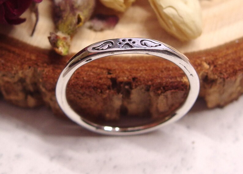 May include: A silver ring with a paw print and angel wings engraved on the band.