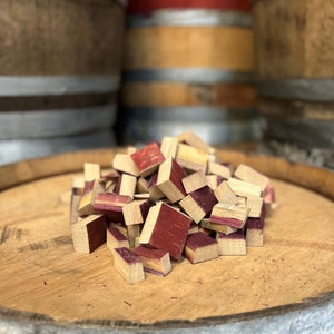 May include: A pile of small, wooden cubes with a reddish-brown color. The cubes are made from reclaimed wine barrels and are used for smoking food.