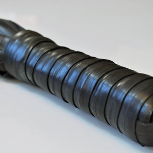 May include: A black whip made from multiple strips of rubber, wrapped with black tape.