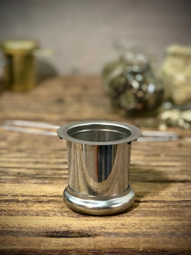 Puede incluir: Un infusor de t&eacute; de acero inoxidable con un filtro de malla fina. El infusor tiene una base redonda y un cuerpo cil&iacute;ndrico.