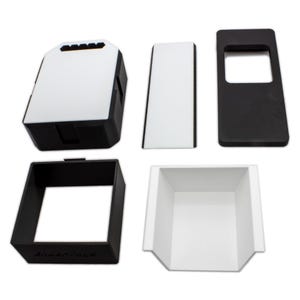 May include: An assortment of black and white plastic components, likely for a larger product. The pieces include a rectangular box with a white top, a rectangular frame, and a tray-like structure. The components are arranged against a white background.