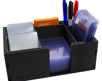 May include: A black desk organizer with multiple compartments. It holds pens, markers, sticky notes, and stacks of clear card sleeves. The organizer is designed to keep items neatly arranged and accessible.