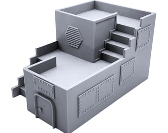 May include: A gray, two-story building with a flat roof and a small, hexagonal vent on the side. The building has a set of stairs leading up to the second floor and several square, metal panels with rivets on the exterior.
