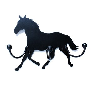 May include: Black metal horse silhouette wall hook with two hooks. The horse is running and has a long tail. The hooks are on the horse's neck and tail.