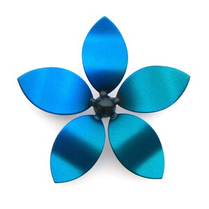 May include: A blue metal flower with five petals. The petals are a gradient of blue and teal.