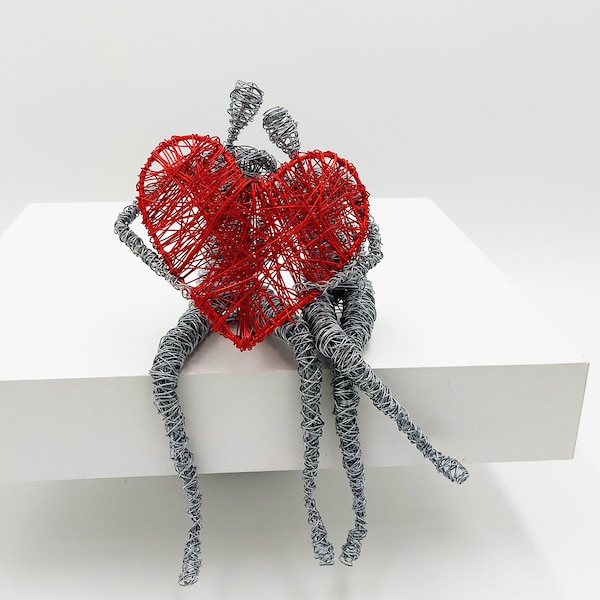Scultura in filo d'amore duraturo, coppia che tiene un cuore rosso