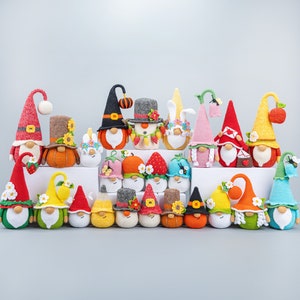 Puede incluir: Una colección de 20 adornos de gnomos de crochet en varios colores y diseños. Los gnomos llevan sombreros, bufandas y otros accesorios. Algunos gnomos sostienen flores, calabazas y otros objetos.