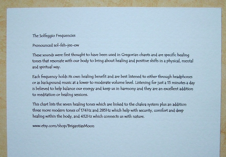 Op de afbeelding: Een witte kaart met blauwe tekst die de Solfeggio-frequenties uitlegt, een reeks helende tonen. De tekst legt uit dat de tonen naar verluidt werden gebruikt in Gregoriaanse gezangen en dat ze naar verluidt helpen om energie te balanceren en genezing te bevorderen. De kaart bevat ook een website-adres: www.etsy.com/shop/BrigantiasMoon.