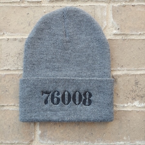 May include: Gray knitted beanie with the number 76008 embroidered in black.