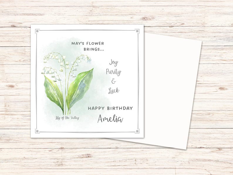 Puede incluir: Tarjeta de cumplea&ntilde;os con una ilustraci&oacute;n de acuarela de lirios de los valles. La tarjeta incluye el texto: "May's Flower Brings... Joy, Purity & Luck. Happy Birthday Amelia." Se incluye un sobre blanco.
