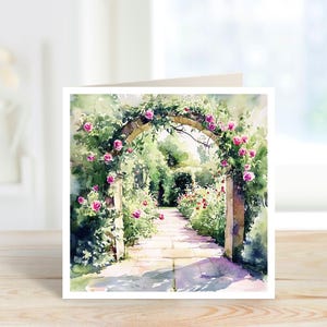 May include: Watercolour painting of a garden path leading to an arched entrance adorned with pink roses. The path is flanked by verdant foliage and flowers, creating a tranquil scene. The artwork is presented on a white card.