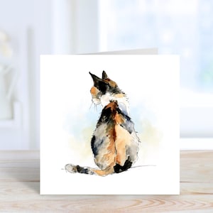 Peut inclure: Une carte de vœux carrée présentant une illustration à l'aquarelle d'un chat calico vu de dos. Le chat présente des taches de fourrure noire, orange et blanche, avec un fond en lavis aquarelle bleu et jaune sur la surface blanche de la carte.