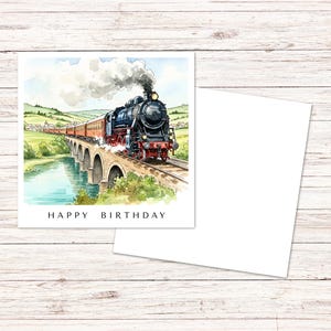 May include: A square greeting card featuring a watercolor illustration of a black steam locomotive pulling red passenger cars across a stone viaduct over a river, with the text HAPPY BIRTHDAY printed in black capital letters at the bottom.
