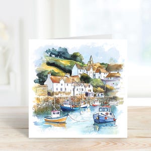K&ouml;nnte beinhalten: Aquarellmalerei eines K&uuml;stendorfes mit wei&szlig;en Geb&auml;uden, roten Ziegeld&auml;chern und einem Kirchturm. Mehrere bunte Boote liegen im Hafen. Das Kunstwerk befindet sich auf einer quadratischen Gru&szlig;karte.