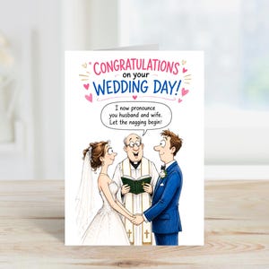 Peut inclure: Une carte de vœux blanche avec une illustration de dessin animé d'une cérémonie de mariage. Le texte indique : CONGRATULATIONS on your WEDDING DAY ! Une bulle de l'officiant dit : I now pronounce you husband and wife. Let the nagging begin !