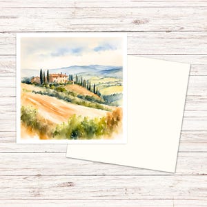 May include: A square greeting card featuring a watercolor painting of a Tuscan landscape with a stone villa, tall cypress trees, and rolling golden hills under a soft blue sky, accompanied by a matching blank white envelope.