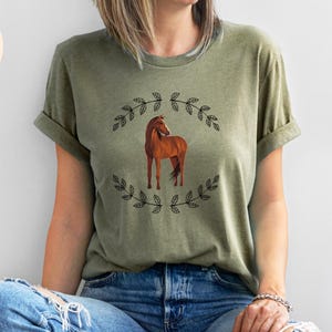 May include: A green t-shirt with a brown horse illustration surrounded by black floral designs. The text "Small Time Products Co." is visible in the top left corner of the image.