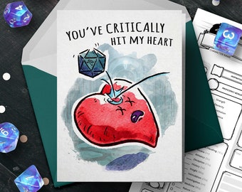 May include: A greeting card with a watercolor illustration of a red heart with a blue dice rolling into it. The card reads "You've critically hit my heart."