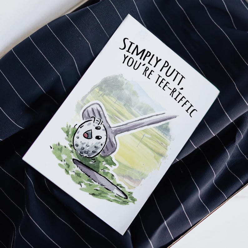 May include: A white card with a watercolor illustration of a golf ball and club. The text on the card reads "Simply Putt, You're Tee-Rific".