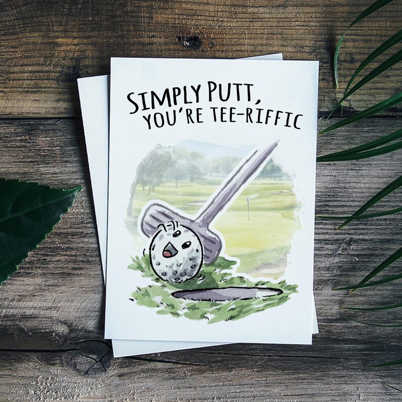 May include: A white card with a watercolor illustration of a golf ball going into a hole. The text on the card reads "Simply putt, you're tee-riffic."