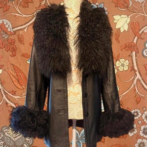 Peut inclure: Veste en cuir noire avec un col et des poignets en fourrure foncée. La veste a une fermeture boutonnée et est présentée sur un mannequin. Le design de la veste présente une texture et un style uniques, adaptés aux vêtements d'extérieur.