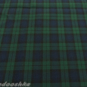 以下が含まれることがあります： 緑、ネイビーブルー、黒のチェック柄の生地のクローズアップ。パターンは、交差する線のグリッドを特徴とし、クラシックなタータンデザインを作成します。生地は織り込まれた素材を示唆する、テクスチャ加工された外観をしています。