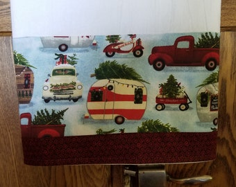 Puede incluir: Una caravana a rayas rojas y blancas con un árbol de Navidad en la parte superior, rodeada de otros vehículos con árboles de Navidad, sobre un fondo azul y blanco. La caravana tiene luces alrededor.