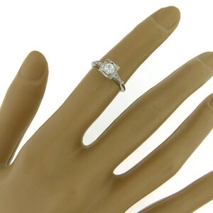 May include: A silver ring with a round, clear center stone and smaller stones on the band.