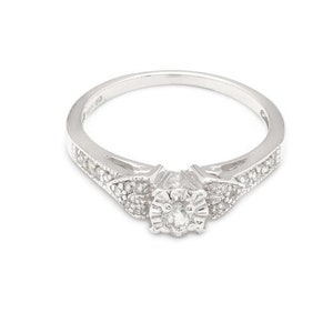 May include: A silver ring with a small round diamond in the center and smaller diamonds set in a floral design on the band.