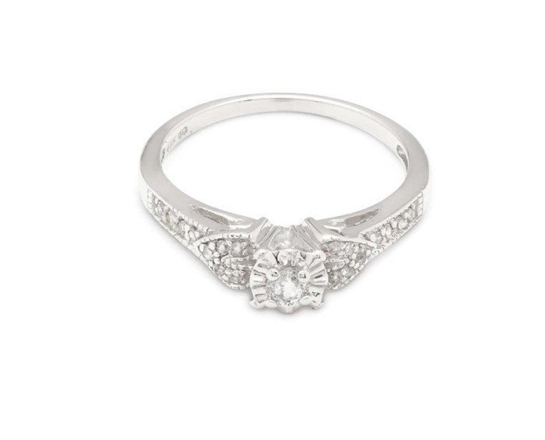 May include: A silver ring with a small round diamond in the center and smaller diamonds set in a floral design on the band.