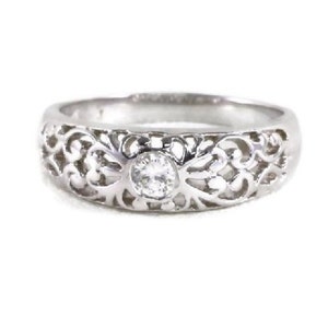 May include: A silver filigree ring with a single clear stone in the center.