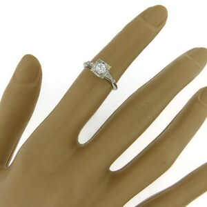 May include: A silver ring with a round, clear center stone and smaller stones on the band.