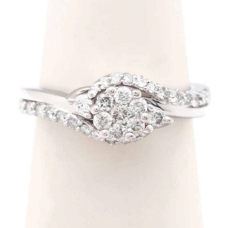 Op de afbeelding: Een zilveren ring met een cluster van diamanten in een swirl-ontwerp.