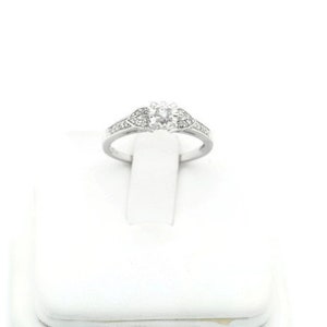 May include: A silver ring with a single round diamond in the center and smaller diamonds set in the band.