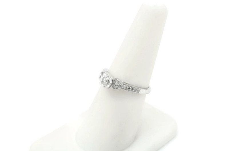 May include: A silver engagement ring with a central diamond and smaller diamonds set in a delicate band.