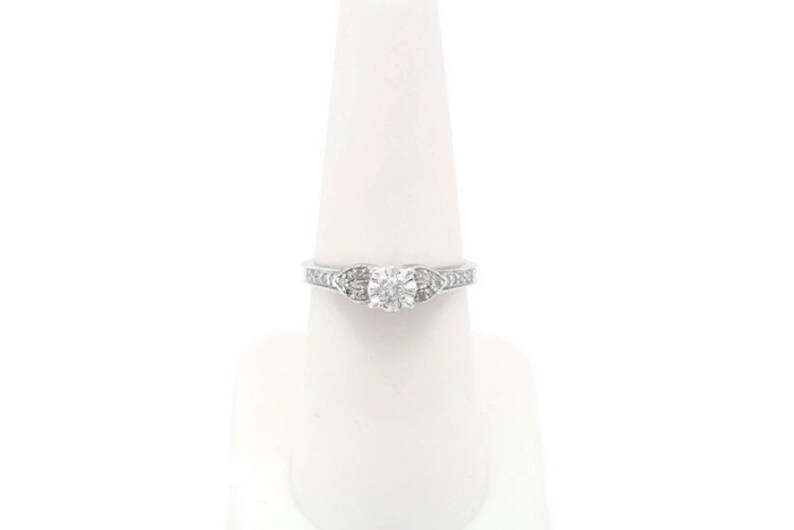 May include: A silver engagement ring with a round center diamond and smaller diamonds set in the band.