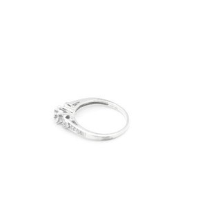 May include: A silver ring with a small cluster of diamonds in the center and smaller diamonds set along the band.