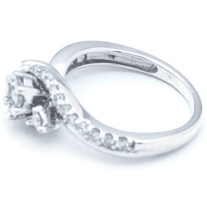 Op de afbeelding: Een zilveren ring met een cluster van kleine diamanten die in een swirl-ontwerp zijn gezet. De ring heeft een gepolijste afwerking en is geplaatst op een witte achtergrond.